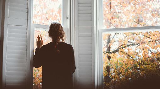 Imagen de archivo de una mujer mirando por la ventana.