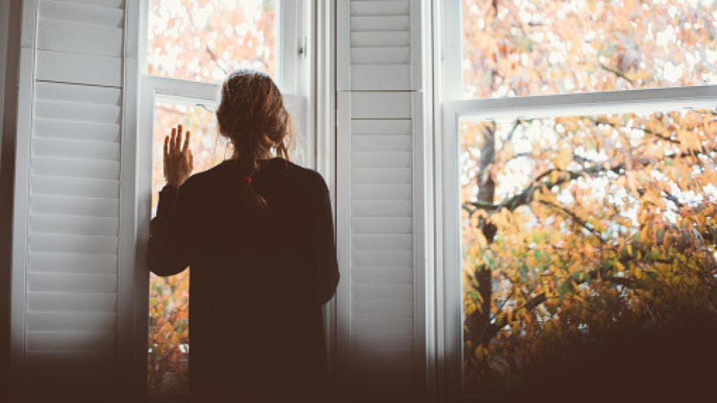Imagen de archivo de una mujer mirando por la ventana.