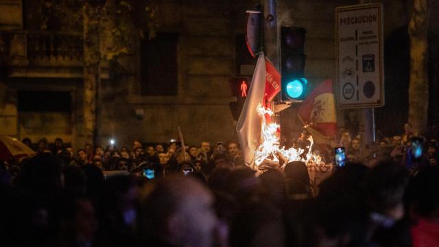 Los manifestantes queman unos carteles pegados en un semáforo en la calle de Ferraz.