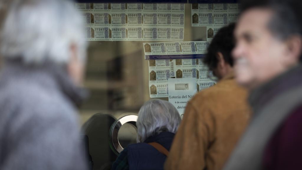 Varias personas hacen cola para comprar lotería en Sevilla.