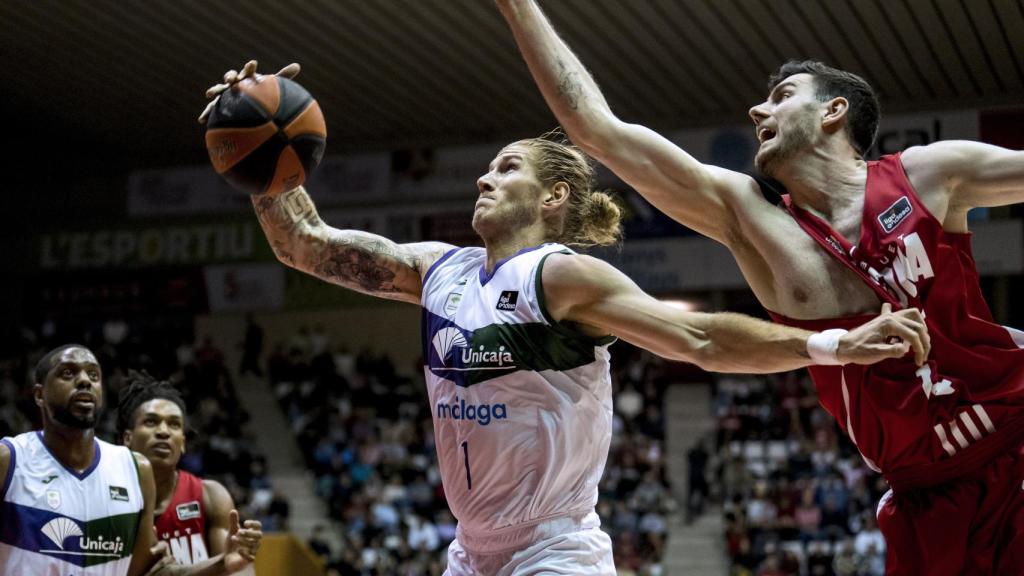 El ala pívot estadounidense del Unicaja Málaga Dylan Osetkowski (i) supera al alero húngaro del Girona György Goloman, durante el partido de Liga Endesa que se disputa este sábado en el pabellón de Fontajau.