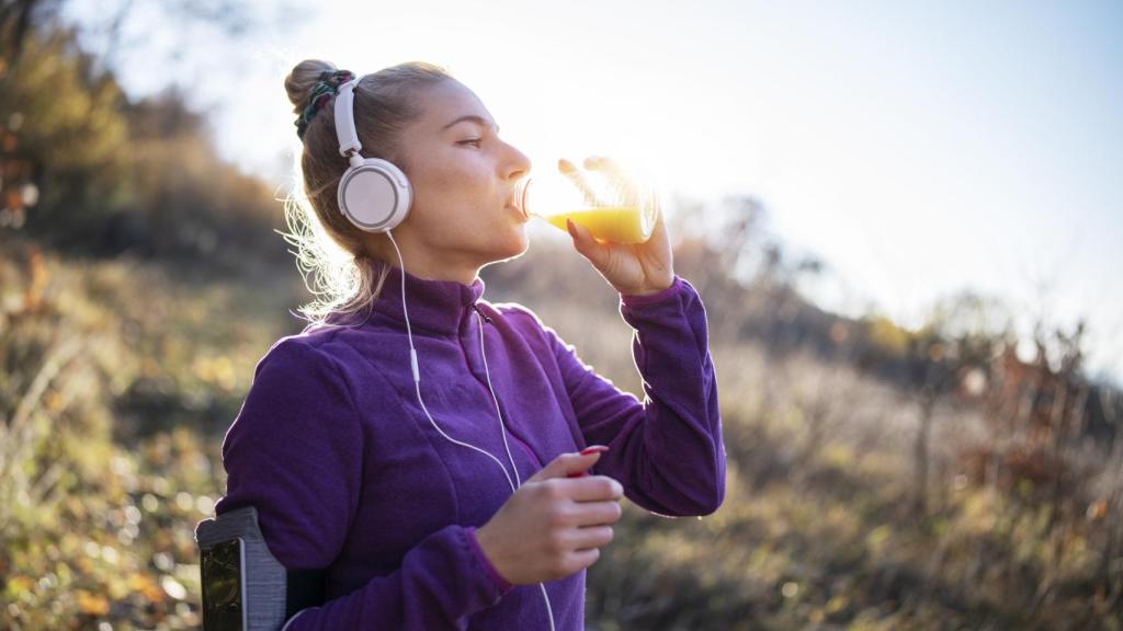 Imagen de una mujer haciendo deporte en la montaña tomando un zumo