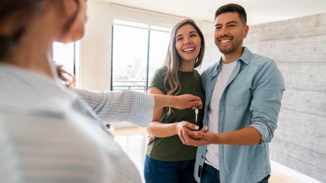 Una vendedora entrega las llaves a los nuevos dueños.