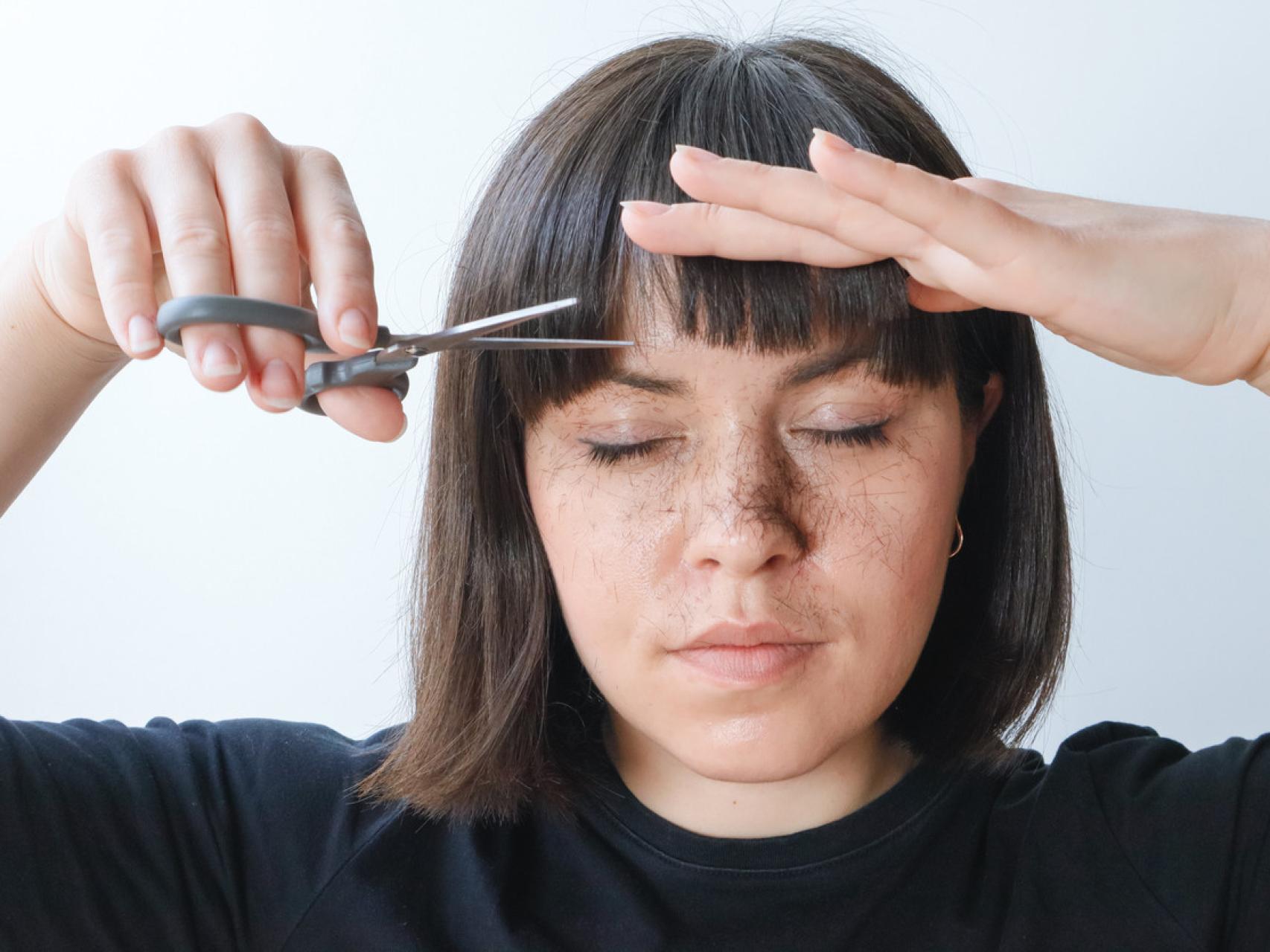 Chica cortándose el flequillo.