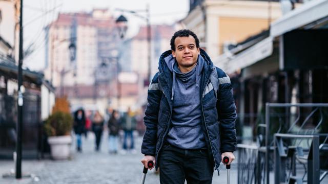 Un hombre de baja laboral con muletas en la calle.