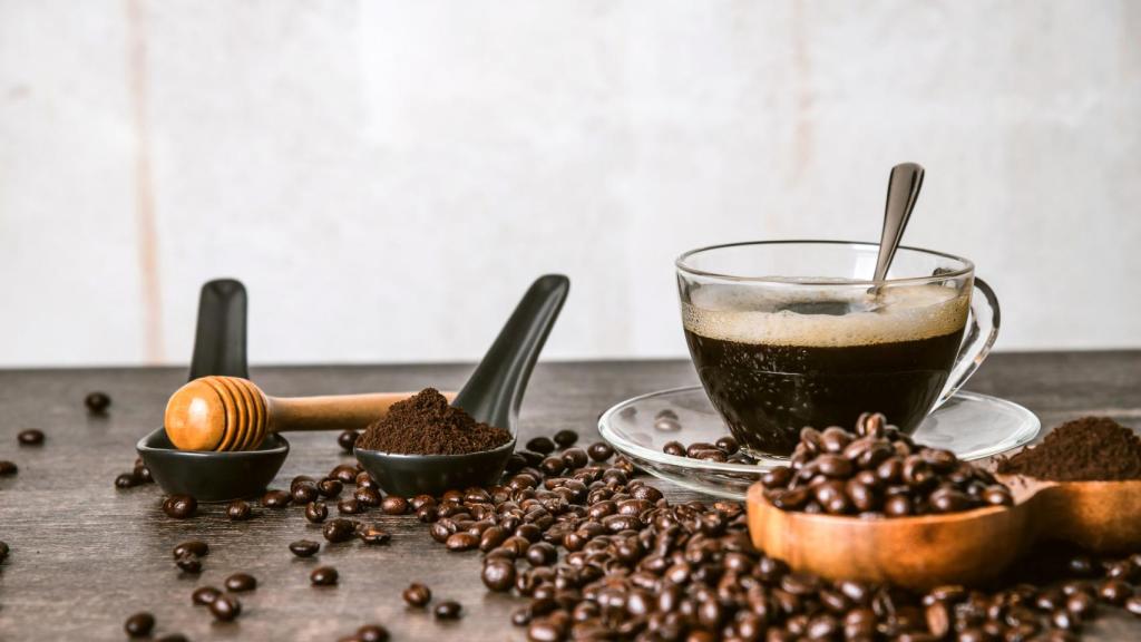 Taza de café, junto a granos de café tostado y molido.