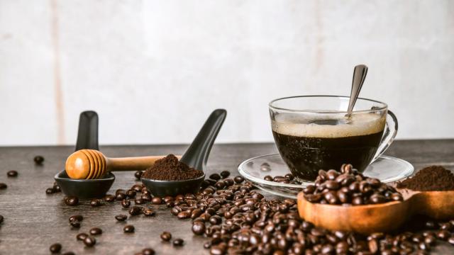 Taza de café, junto a granos de café tostado y molido.