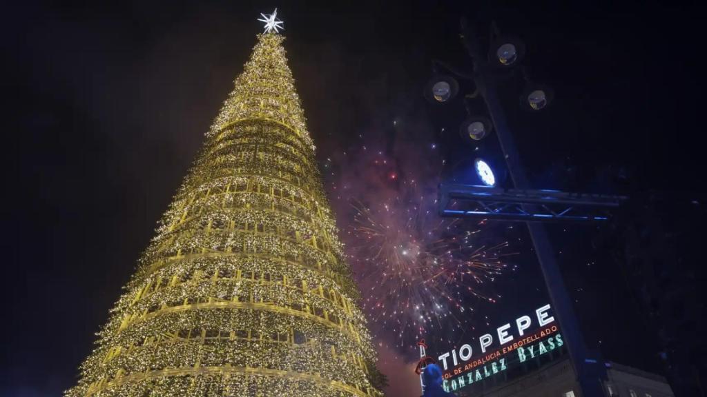 El árbol de la Puerta del Sol tras el encendido de este 23 de noviembre y bajo los fuegos artificiales.