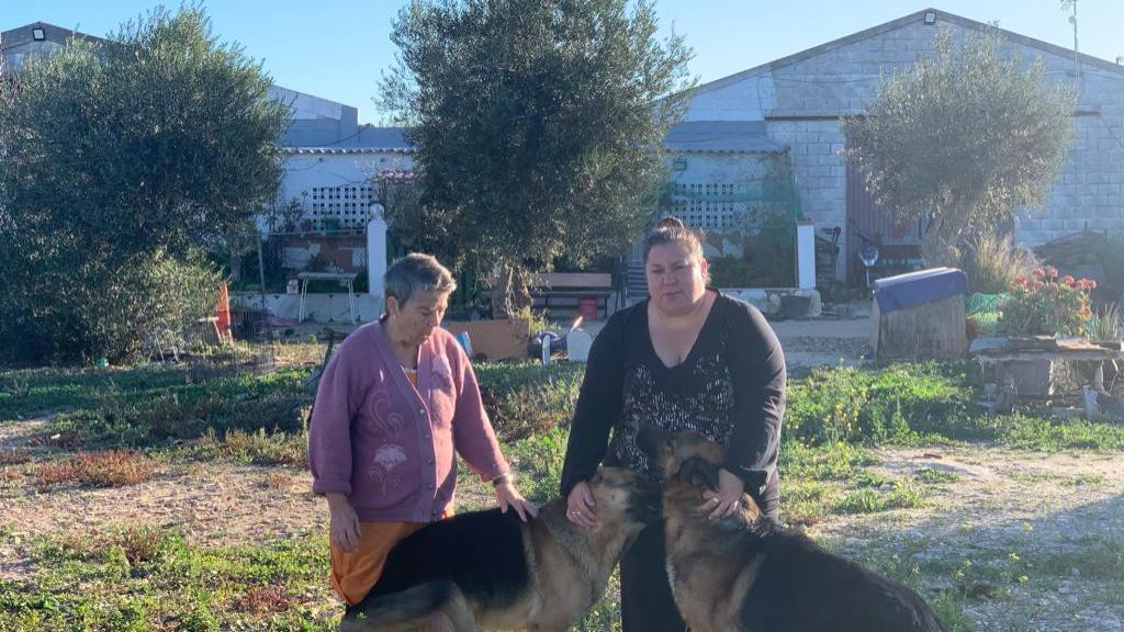 Lorenza y su hija Maribel, delante de la vivienda y de las naves 'okupadas'.