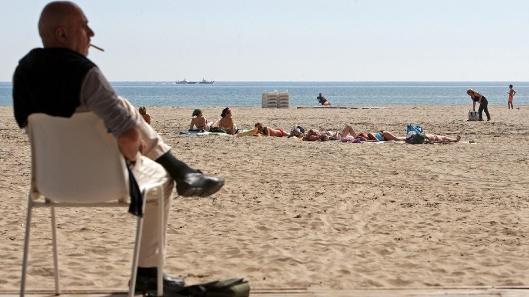 Un hombre fumando en una playa.