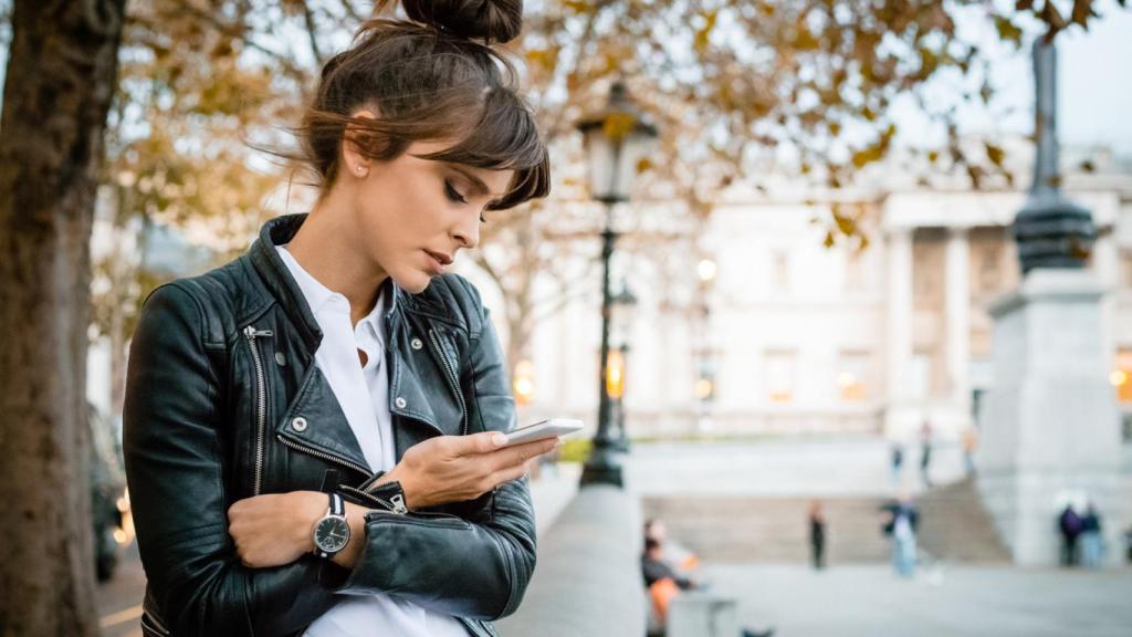 Mujer mirando su teléfono móvil con cara de preocupada.