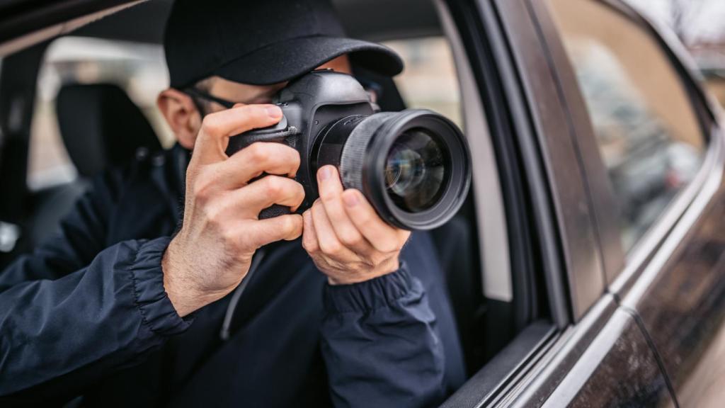 Un detective hace fotografías desde un coche.