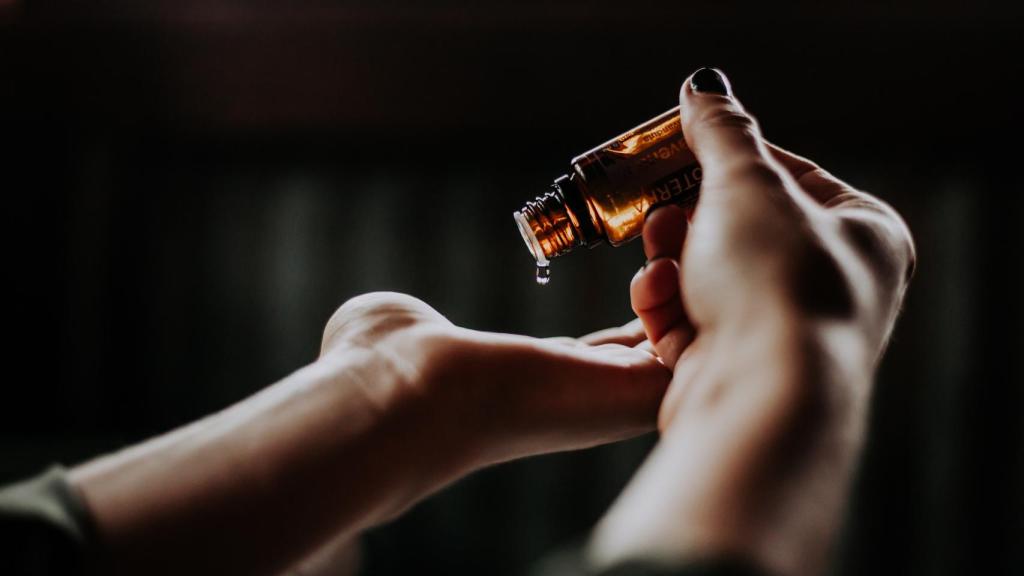 Imagen de unas manos sujetando un bote de aceite esencial