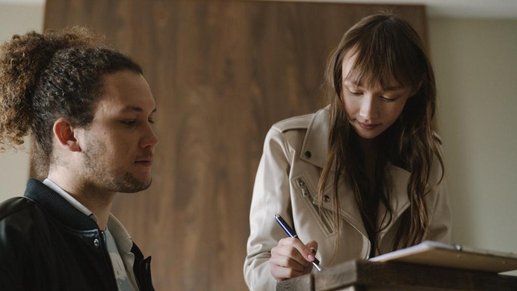 Imagen de dos jóvenes firmando un contrato de alquiler