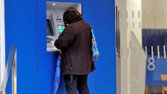 Una mujer saca dinero de un cajero