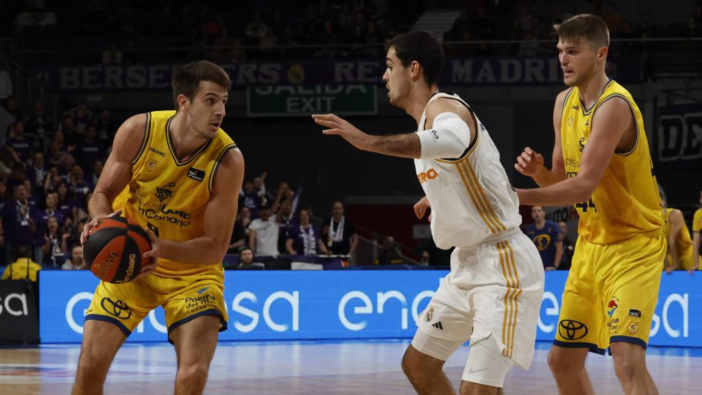 El escolta argentino del Gran Canaria Nicolas Brussino (i) controla un balón ante Alberto Abalde (c) alero del Real Madrid.