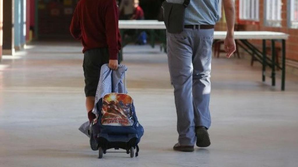 Un alumno entra a su colegio junto a su padre en una imagen de archivo