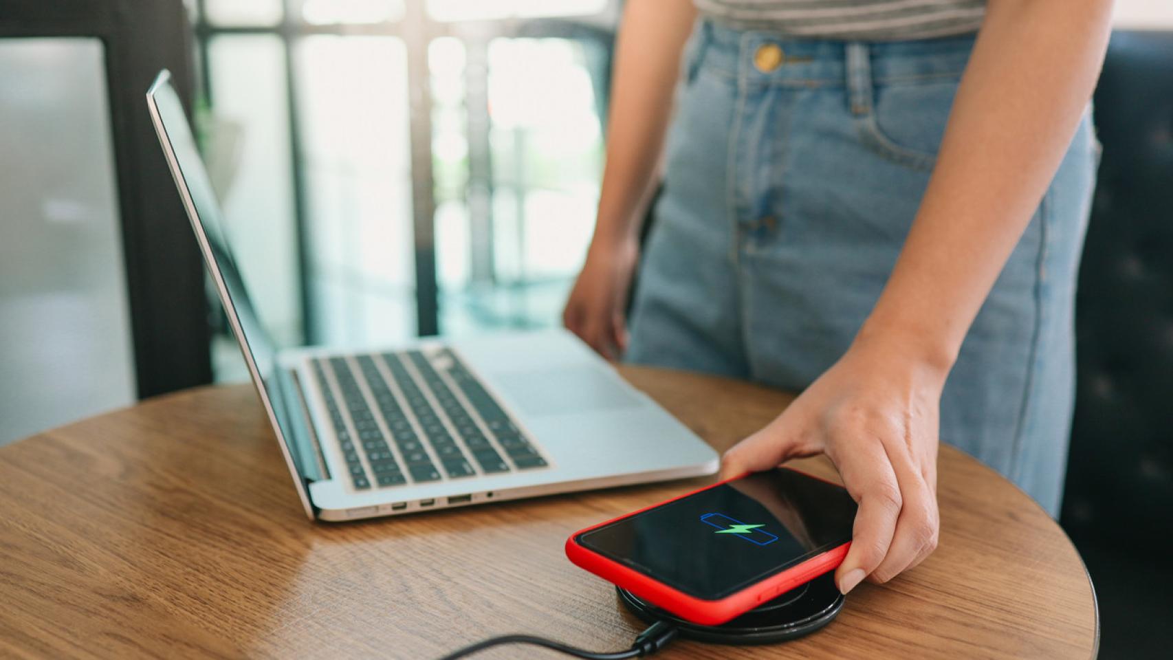 Mujer poniendo a cargar su móvil en un dispositivo inalámbrico.