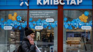 Mujer hablando por teléfono delante de una tienda de Kyivstar en Ucrania