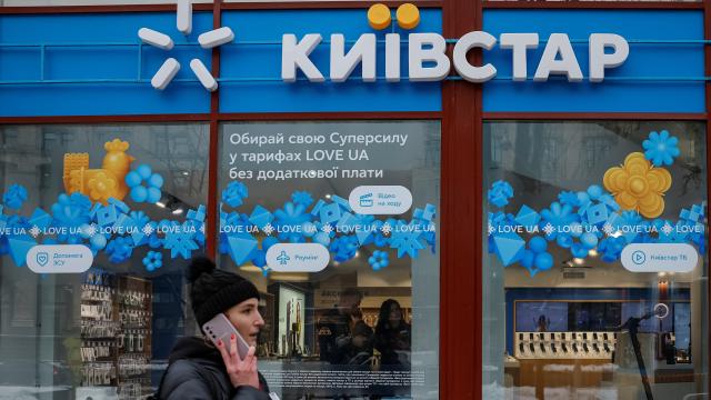 Mujer hablando por teléfono delante de una tienda de Kyivstar en Ucrania