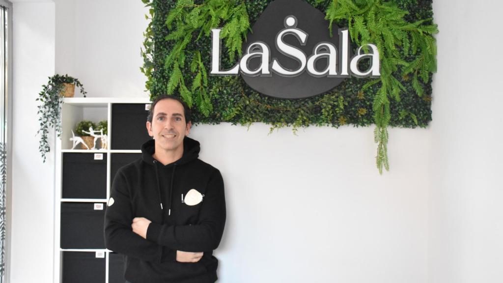 Álex con el cartel de su negocio al fondo