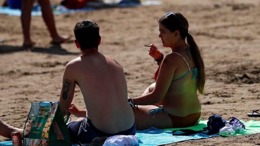 Una mujer fumando en la playa.