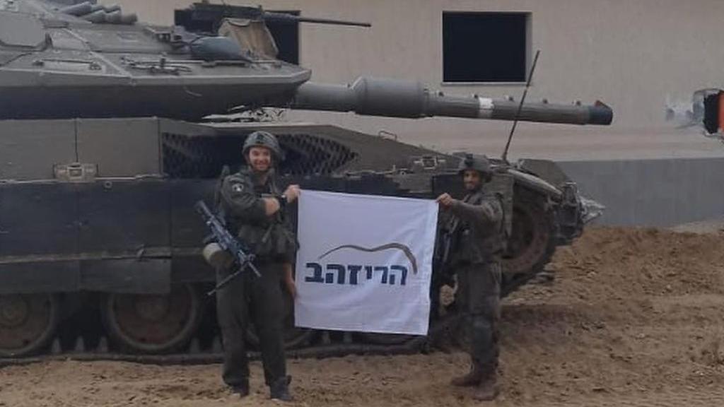Dos soldados israelíes dentro de la Franja de Gaza sostienen una tela con el logo de Harey Zahav.