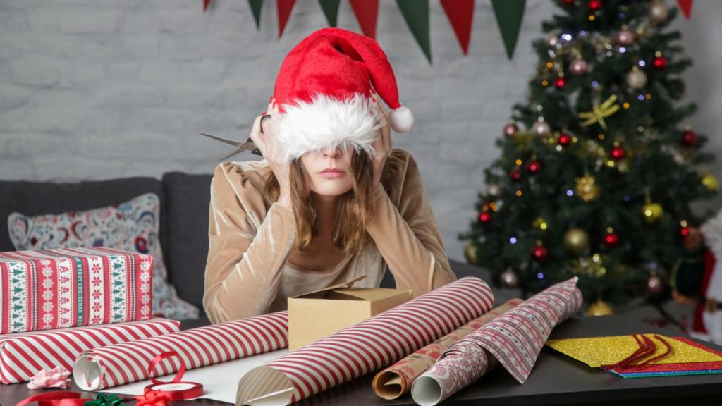 Mujer agobiada envolviendo regalos.