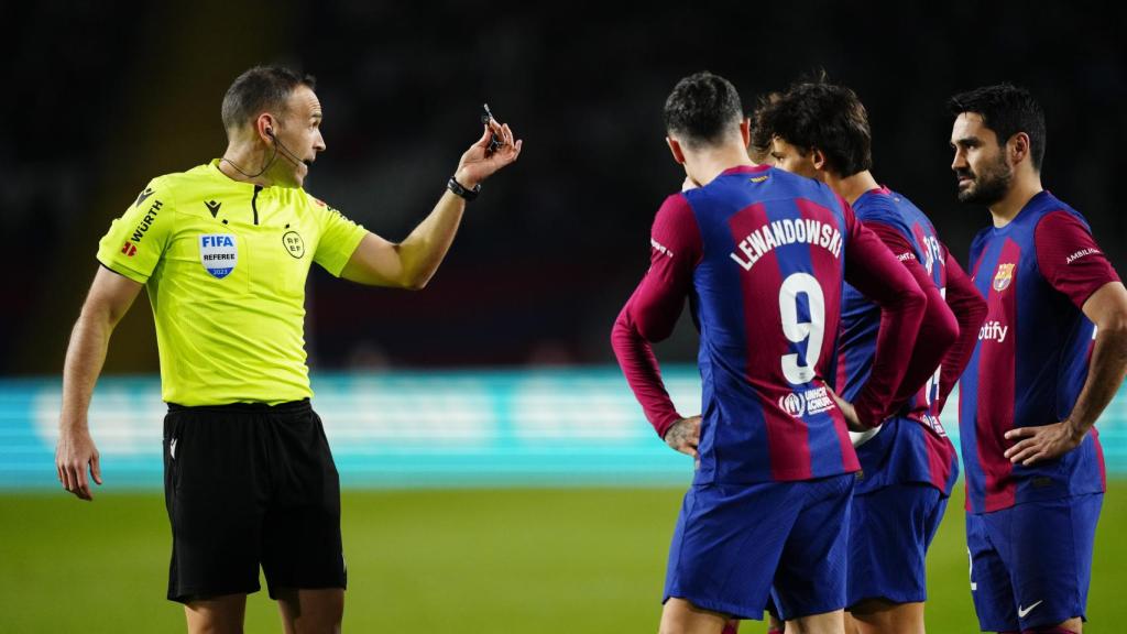 El colegiado da pautas a los jugadores del Barcelona.