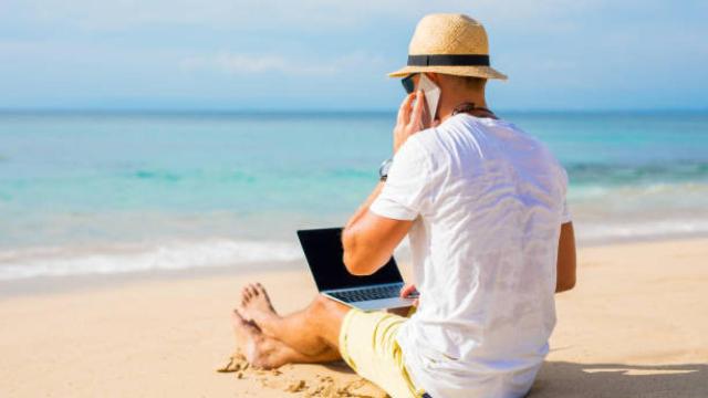Una persona teletrabajando desde una playa de España