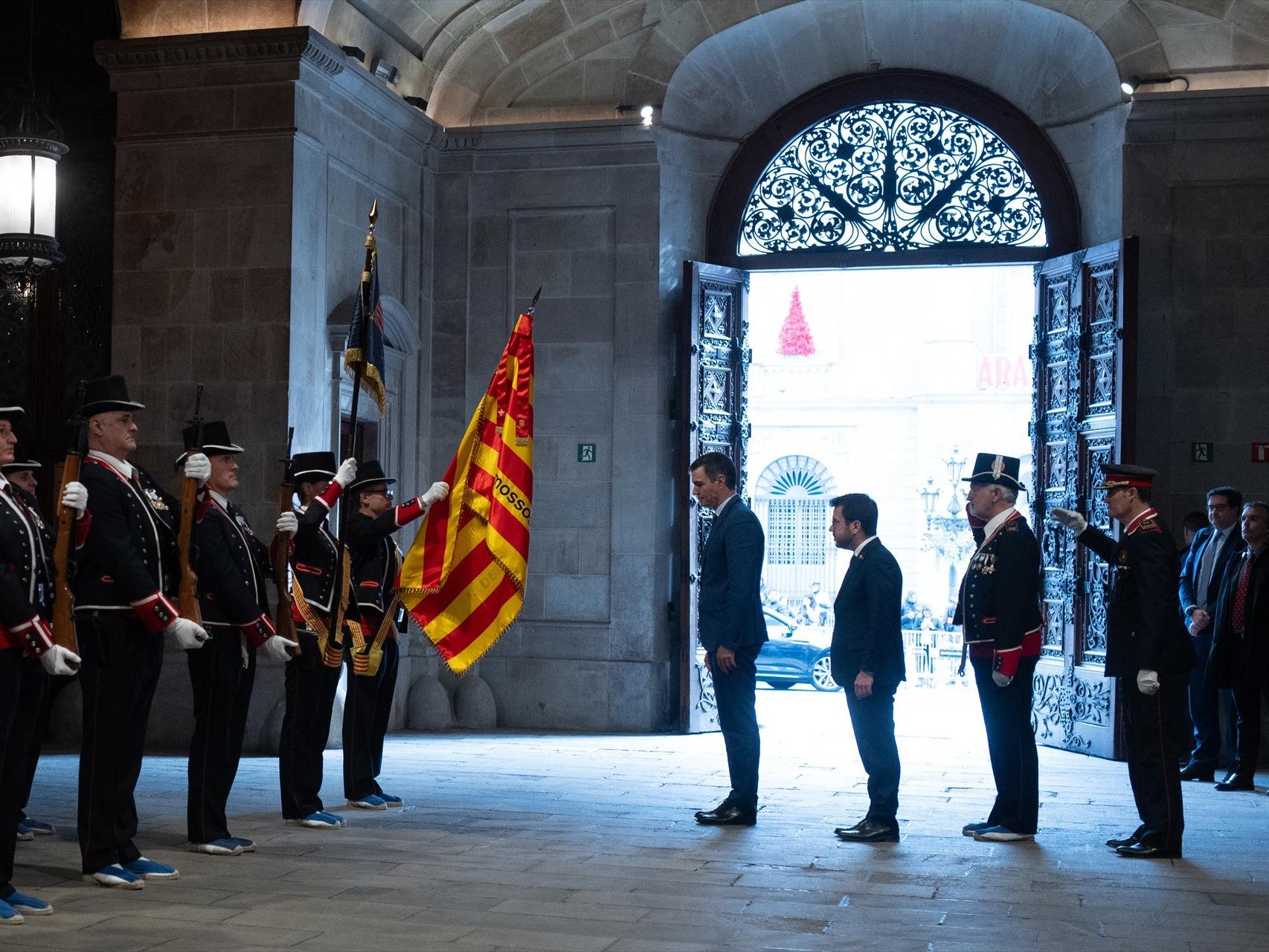 Pedro Sánchez y Pere Aragonès se inclinan ante la señera, antes de su reunión en el Palau de la Generalitat.