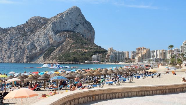 Turistas en la playa de Calpe con el peñón de Ifach al fondo.