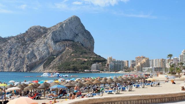 Turistas en la playa de Calpe con el peñón de Ifach al fondo.