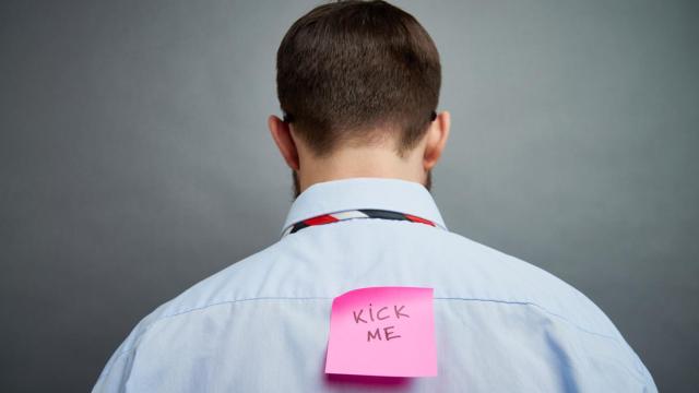 Imagen de archivo de una persona con un posit pegado en la espalda.