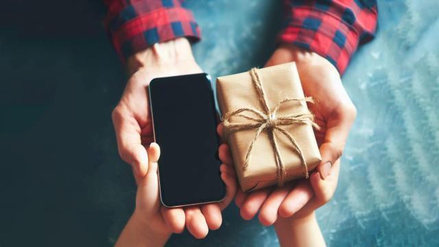 Un padre dando un móvil de regalo a su hijo