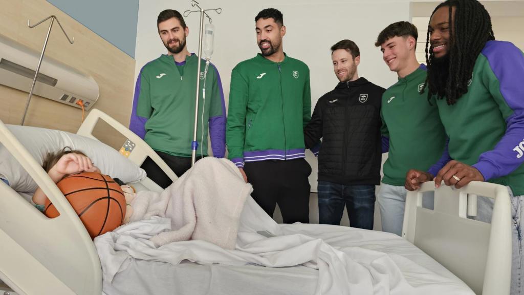Los jugadores del Unicaja Baloncesto visitan a uno de los niños ingresados y le dan un balón.