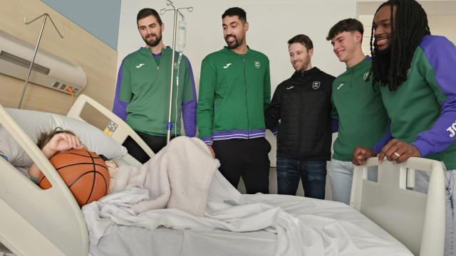 Los jugadores del Unicaja Baloncesto visitan a uno de los niños ingresados y le dan un balón.