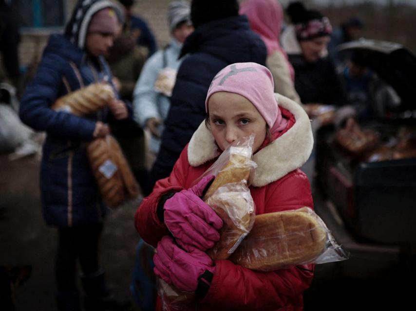 La pequeña Anastia recoge comida repartida por los voluntarios cerca de Jersón.