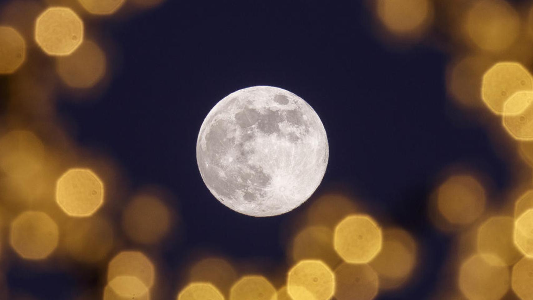 La luna llena vista desde las iluminaciones navideñas en Zaragoza este martes.