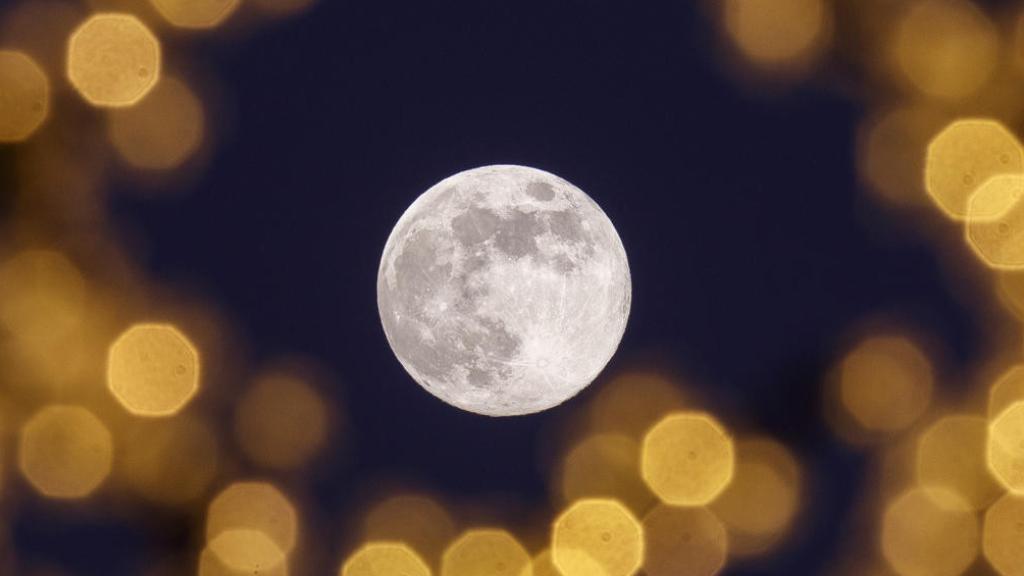 La luna llena vista desde las iluminaciones navideñas en Zaragoza este martes.