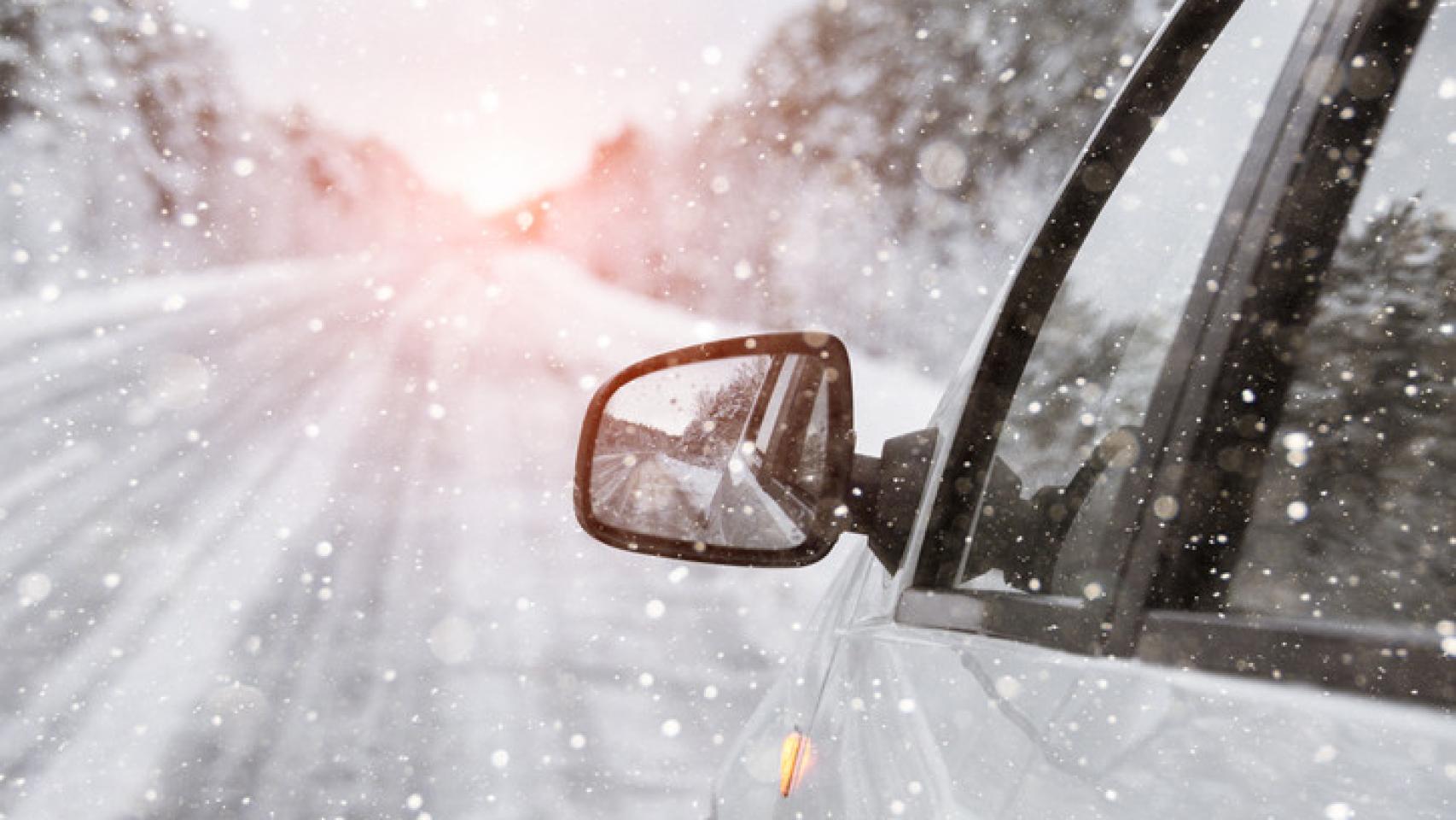Imagen de una coche circulando por una carretera nevada