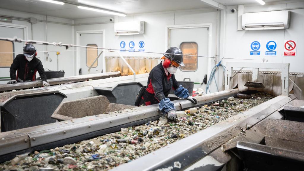 Operarios de Calcín Ibérico separan manualmente, durante una de las fases del proceso de reciclado, los impropios del vidrio.