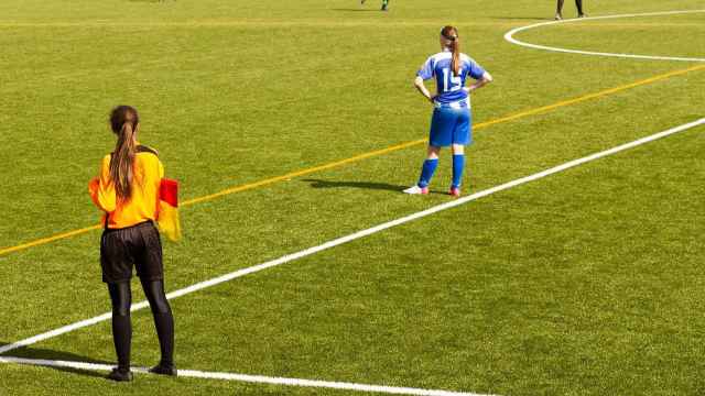 Un partido de fútbol femenino con una asistente árbitra.