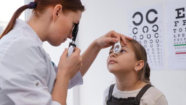 Oftalmólogo pediatra haciendo una revisión a una niña.