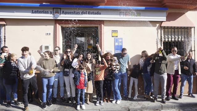 Varias personas celebran los décimos agraciados tras tocarles parte del tercer premio, 18918, de la Lotería del Niño 2023.