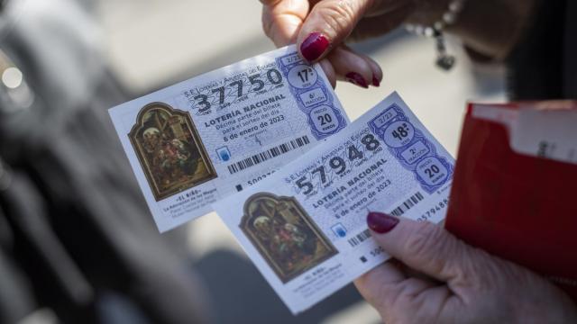 Una mujer sujetando dos décimos de la Lotería del Niño.