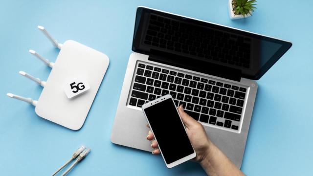 Imagen de un router junto a un ordenador y un teléfono.