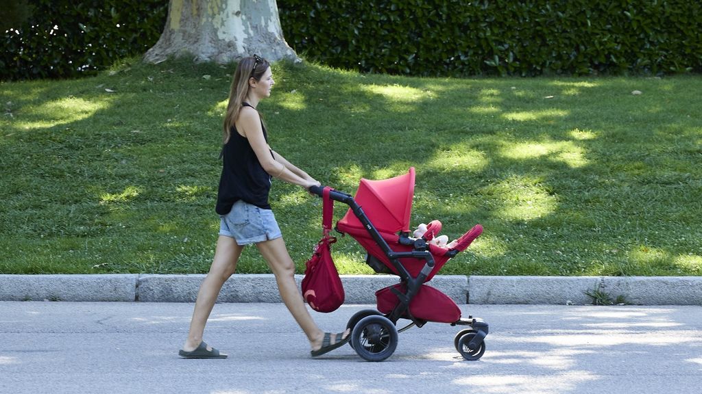 Una mujer pasea con un carrito de bebé.
