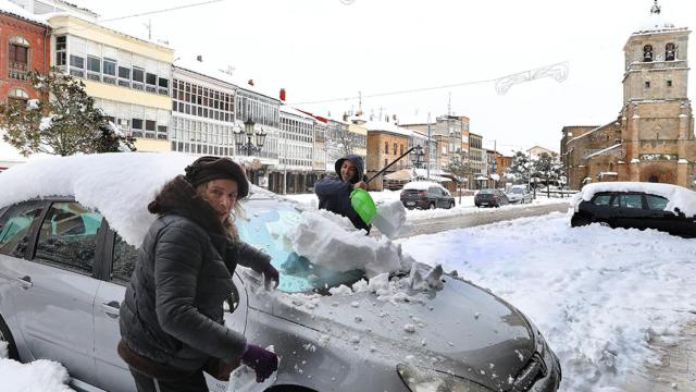 Una pareja retira la nieve de su vehículo en la localidad palentina de Aguilar de Campo
