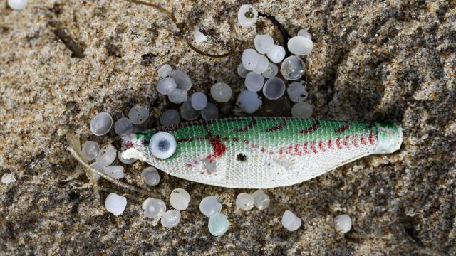 Un pez sintético, empleado como señuelo de pesca, entre varios pellets de plástico